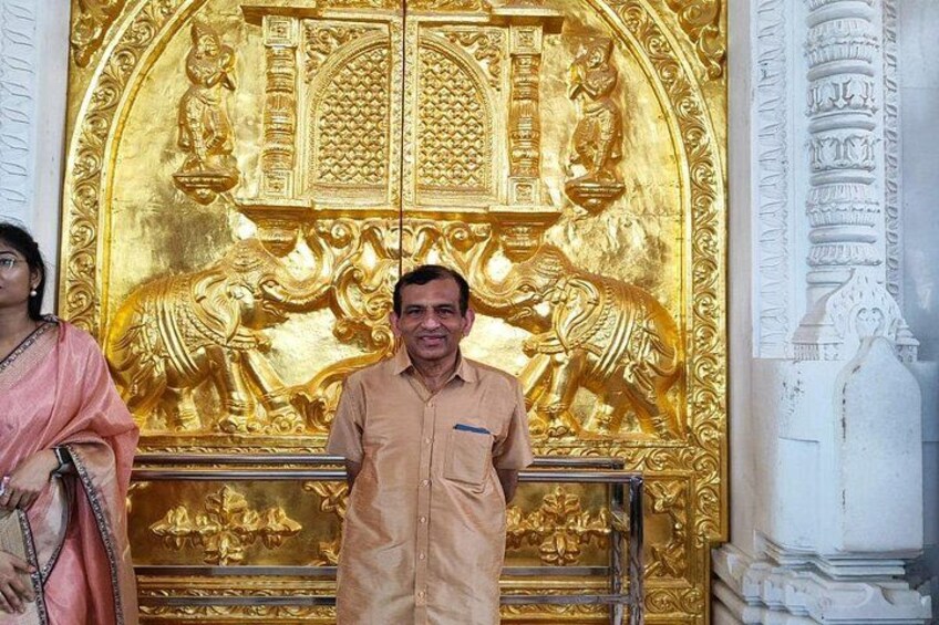 A man standing in front of a golden temple facade with intricate carvings. 4