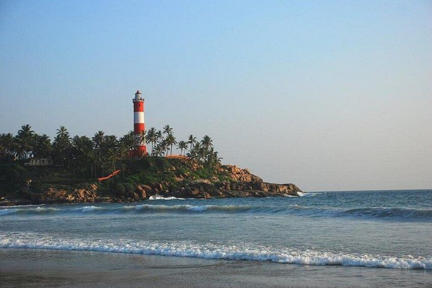 Un faro en un promontorio rocoso rodeado de palmeras y el océano. 2