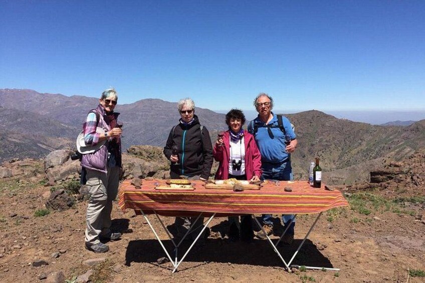 Four people standing by a table with a bottle of wine on a mountain top. 2