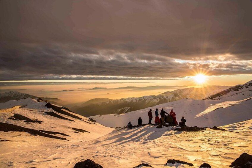 A group of people on a snowy mountain during sunset. 5