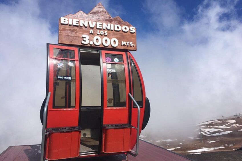 A red cable car with a sign reading 'BIENVENIDOS A LOS 3.000 MTS.' 4