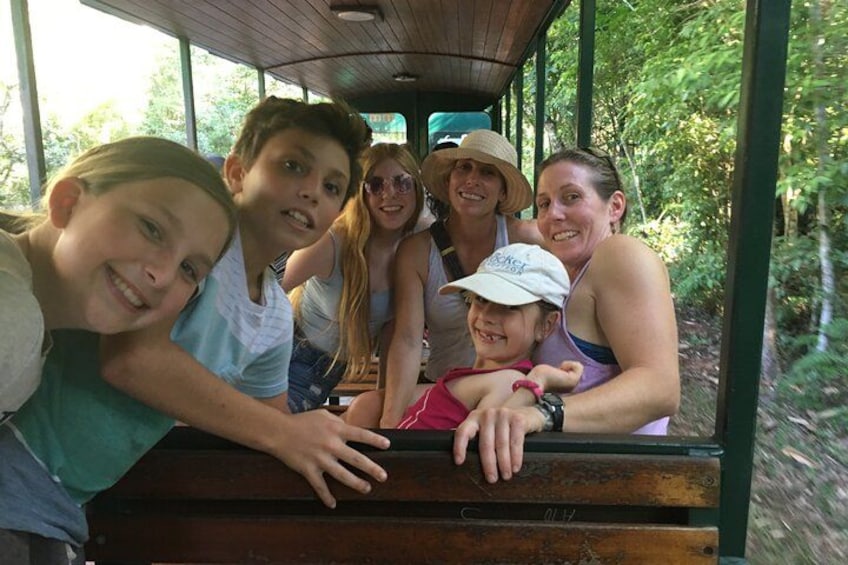 A group of people on a wooden bench in a forested area. 4
