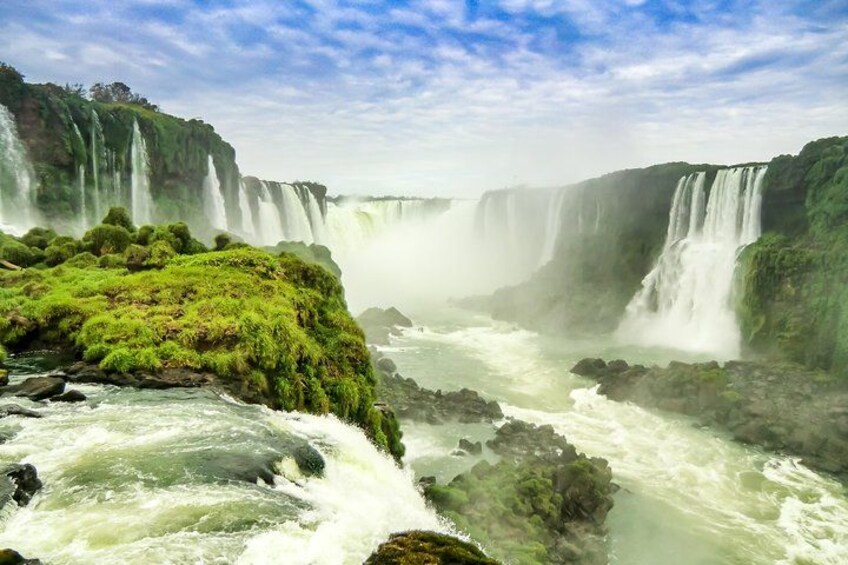 A large waterfall with multiple cascades, surrounded by lush greenery and rocky terrain. 3