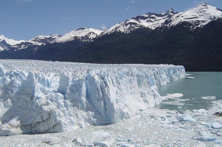 A glacier with a steep ice face and a calm turquoise lake in the background. 2
