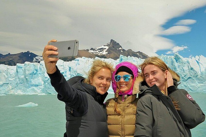 Trois personnes prennent un selfie avec un glacier et des montagnes en arrière-plan. 2
