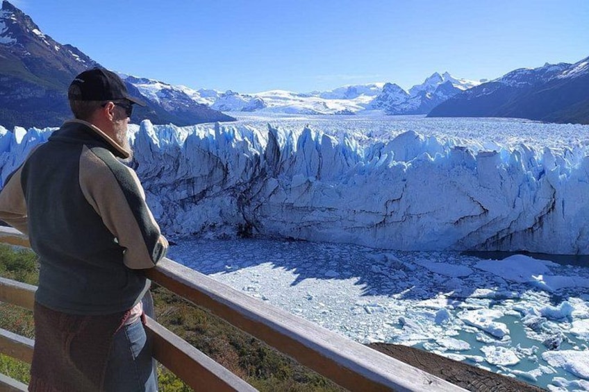 A glacier with a person observing from a railing. 5