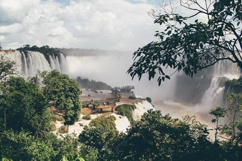 A waterfall with a viewing platform, surrounded by dense foliage. 2