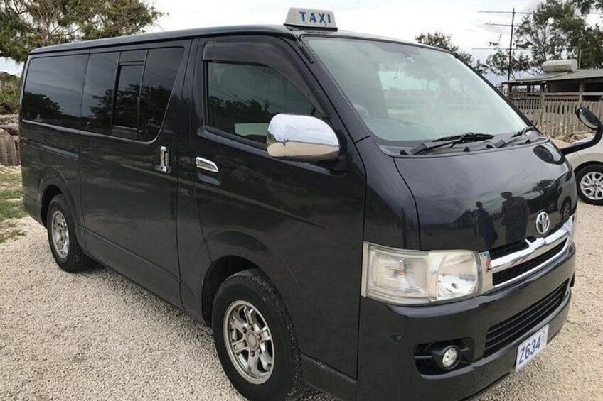 Una camioneta negra con un letrero que dice 'TAXI' en la parte superior, estacionada sobre una superficie de grava. 3