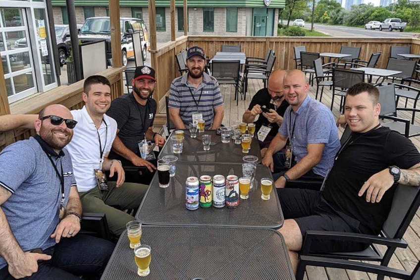 A group of people sitting around a table with drinks and cans of beer. 2