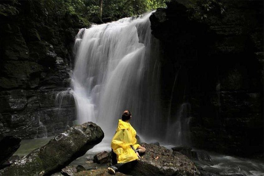 A waterfall, a person in a yellow raincoat, and a rocky landscape. 1