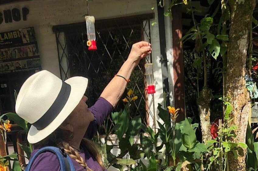 A person wearing a hat and a purple shirt, reaching up to a hanging object. 4