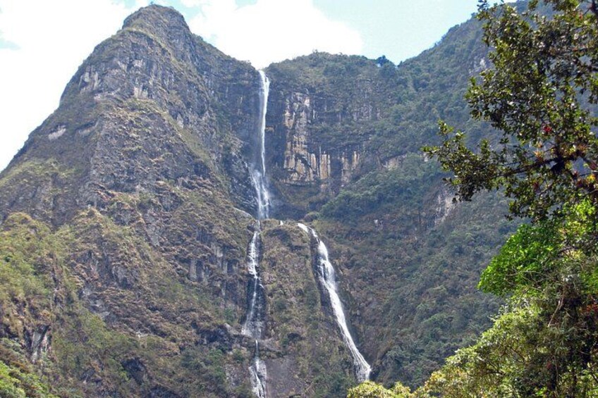 Une cascade se déversant en contrebas d’une falaise abrupte, entourée d’une forêt dense. 1