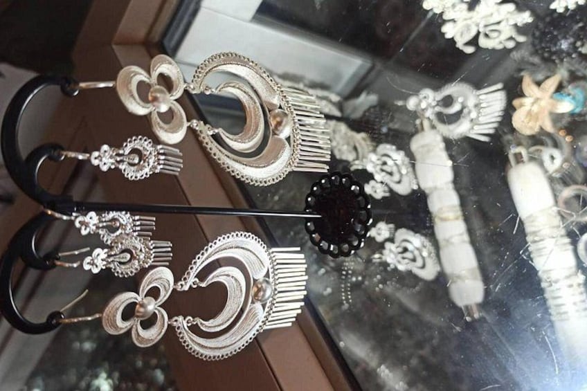 A display of silver earrings with various designs, including flowers and bows, on a glass surface. 3