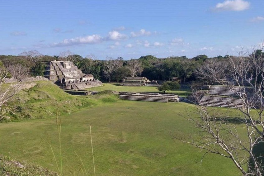 Ancient ruins with stepped pyramids and a grassy field. 3