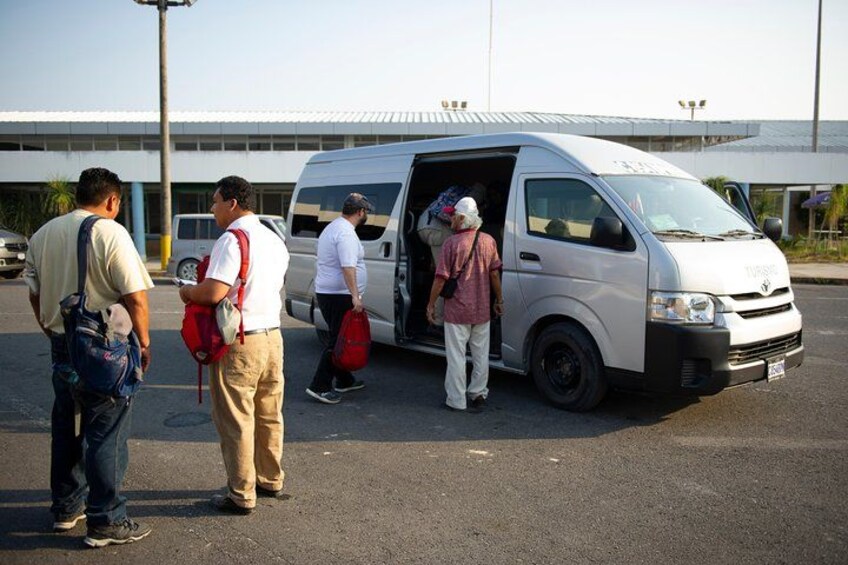 People boarding a white van with a partially open door. 2