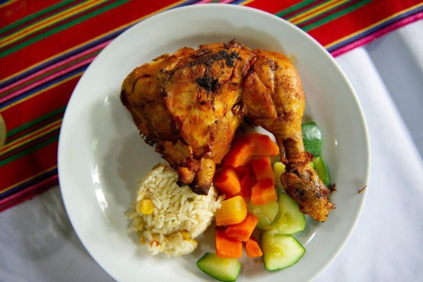 A plate with a roasted chicken leg, rice, and sliced vegetables. 5