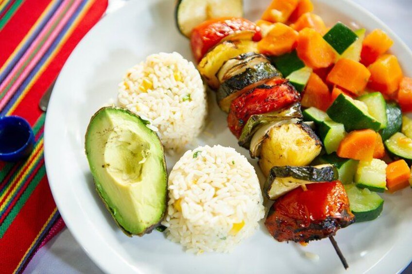 A plate with grilled vegetables, avocado halves, and rice. 4