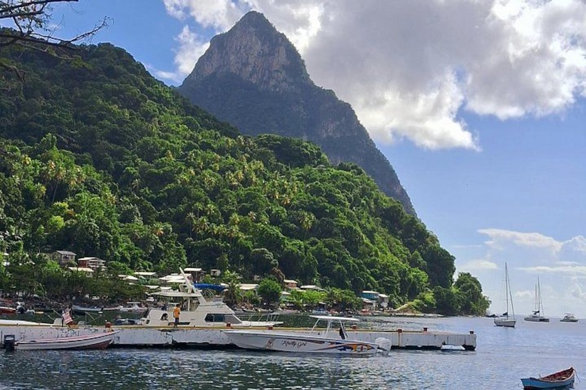 A coastal town with boats docked, a mountain in the background, and sailboats on the water. 2