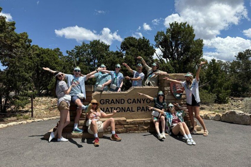 Un groupe de personnes posant devant un panneau indiquant « Parc national du Grand Canyon ». 5