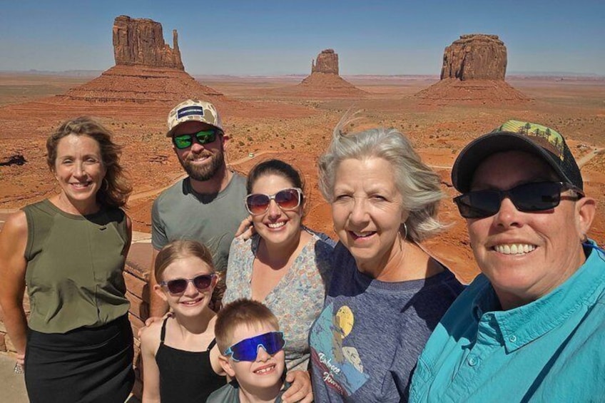 A group of people standing in a desert landscape with rock formations in the background. 3