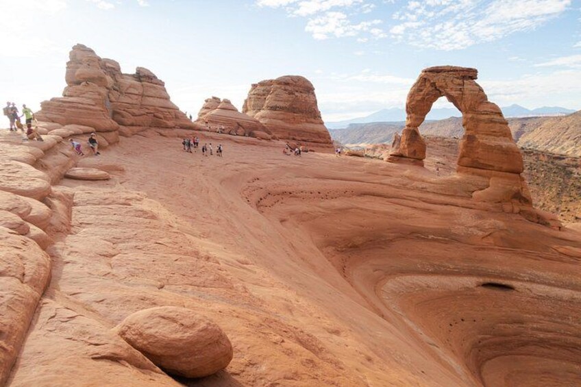 A desert landscape with rock formations and a large arch. 3