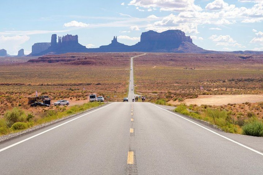A road leading to Monument Valley with a clear sky and distant rock formations. 5