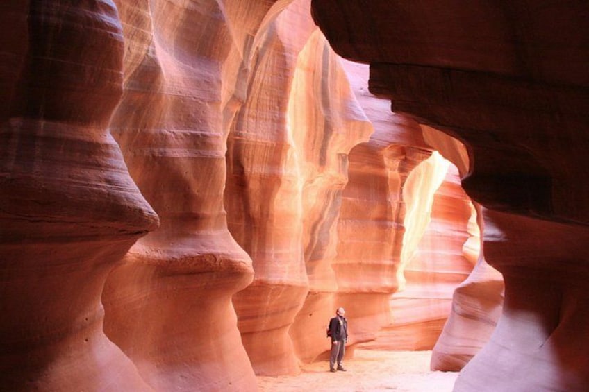 A person standing in a canyon with layered rock formations. 2