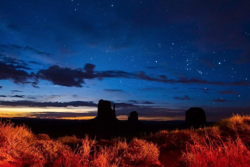A starry night sky over a landscape with rock formations silhouetted against the sky. 3