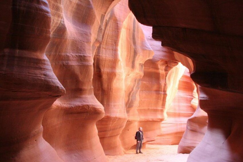 A person standing in a canyon with layered rock formations. 2
