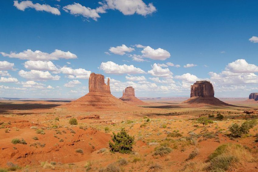 A desert landscape with three prominent rock formations under a clear sky. 4