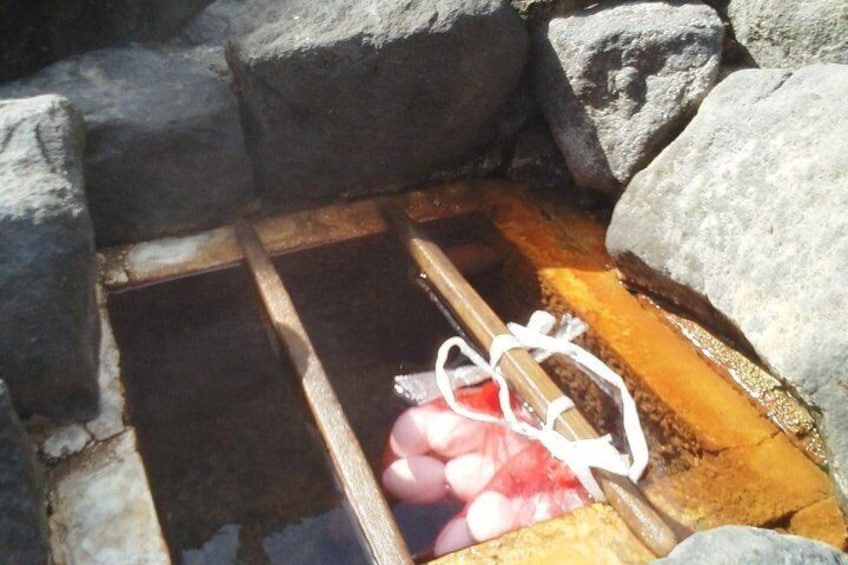 A stone basin with a wooden frame and a white rope. 1