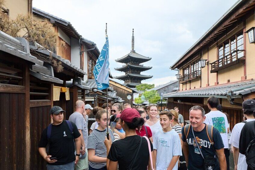 En folkmassa på en traditionell japansk gata med trähus och en pagod i bakgrunden. 5