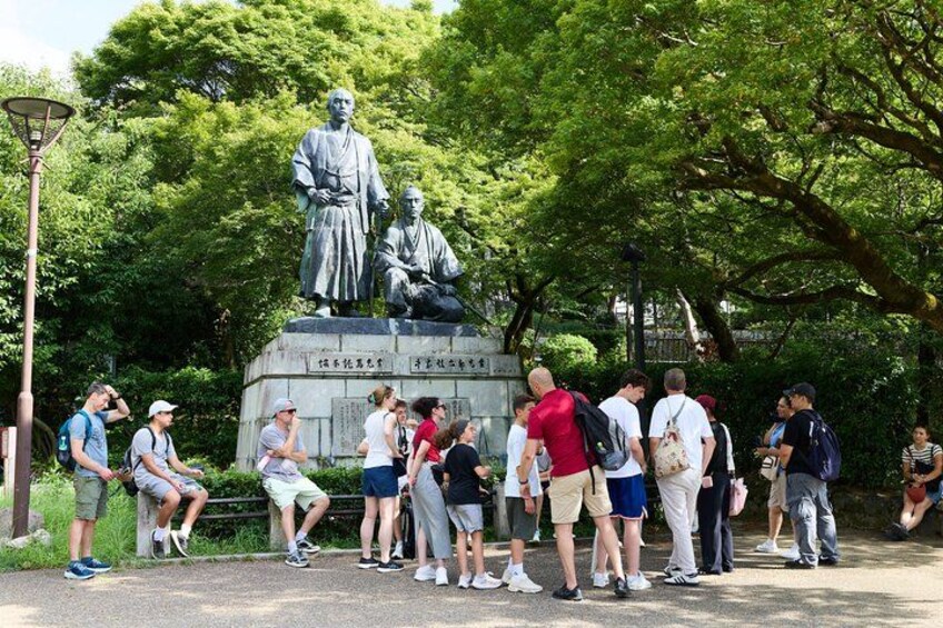 Un grupo de personas reunidas alrededor de una estatua en un parque. 4