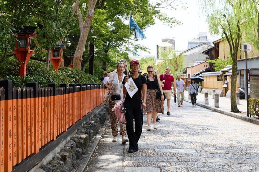 Un sendero de piedra, cerca naranja y faroles tradicionales japoneses. 5