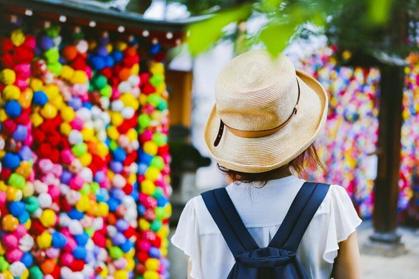 A person wearing a straw hat and a white shirt with suspenders, standing in front of a colorful wall of balloons. 2
