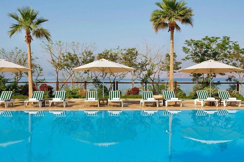 A swimming pool with lounge chairs and umbrellas, palm trees, and a clear sky. 4