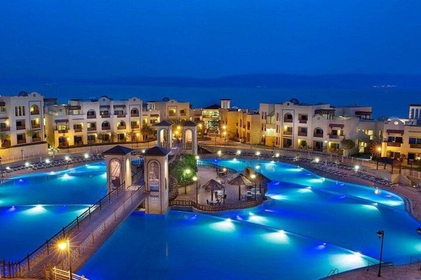 A large swimming pool surrounded by hotel buildings at night. 2