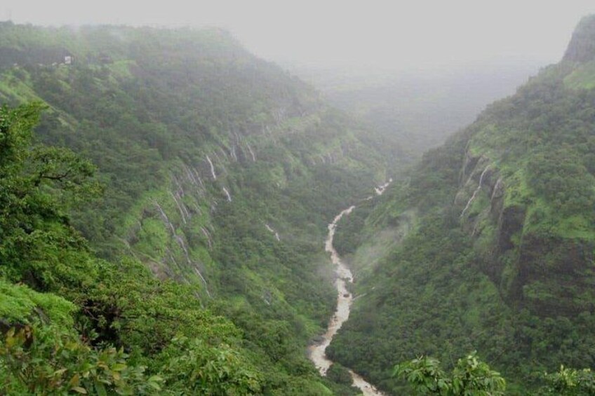 Un río serpentea por un valle verde y exuberante, flanqueado por acantilados pronunciados. 2