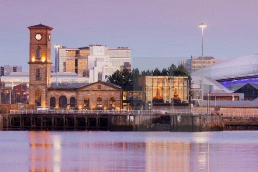 A waterfront cityscape with a clock tower, modern buildings, and a bridge. 1