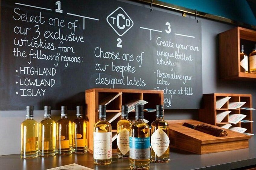 A selection of whisky bottles on a counter with a chalkboard behind them listing steps for a whisky selection process. 3