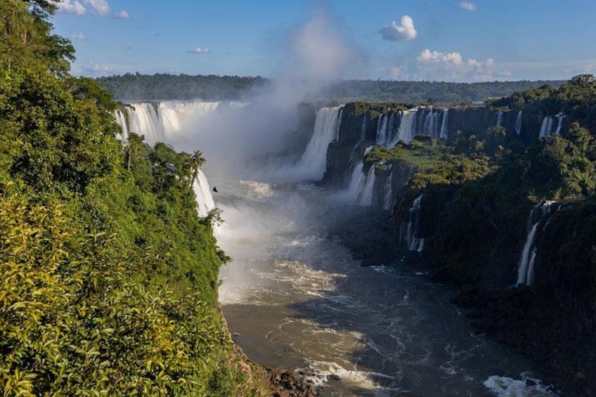 A series of waterfalls cascading down a steep cliff surrounded by dense greenery. 5