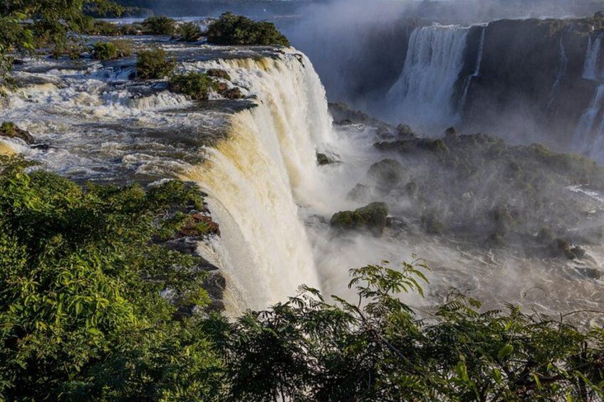 A waterfall cascading over a rocky cliff surrounded by dense vegetation. 2