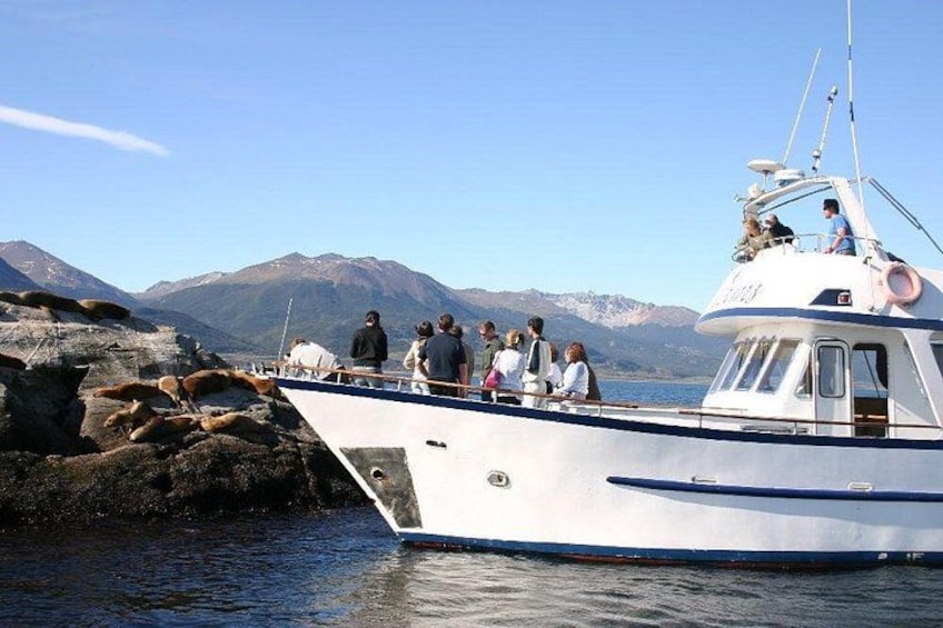 A boat with people on a rocky shore, mountains in the background. 1