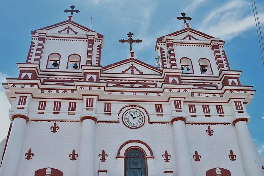 Una iglesia blanca con detalles rojos y un reloj. 3