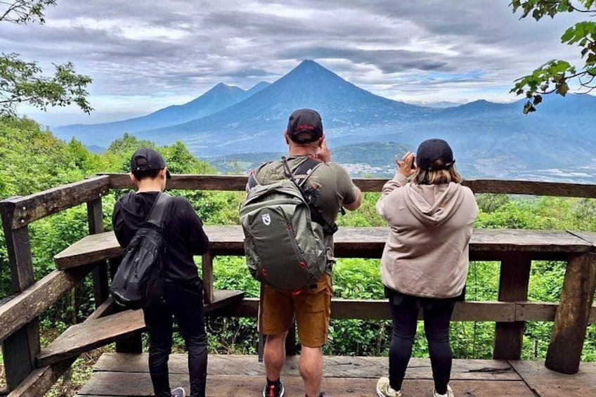 Tres personas en una plataforma de madera, con vistas a una montaña. 1