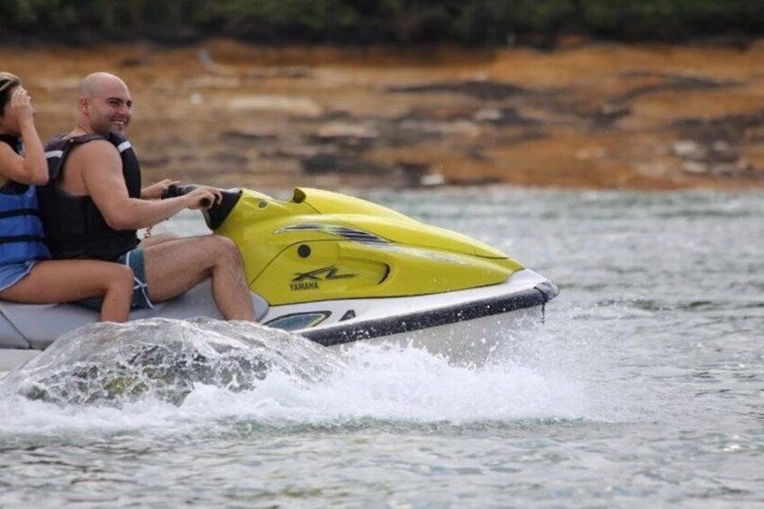 Zwei Personen auf einem gelben Yamaha-Jetski fahren über das Wasser. 3