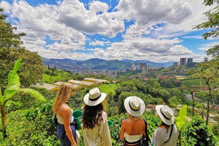 Un grupo de personas con sombreros, de pie en una colina con vistas a una ciudad y montañas al fondo. 1