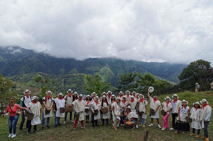 A group of people in white shirts and hats gathered on a grassy hill with a mountainous landscape in the background. 4