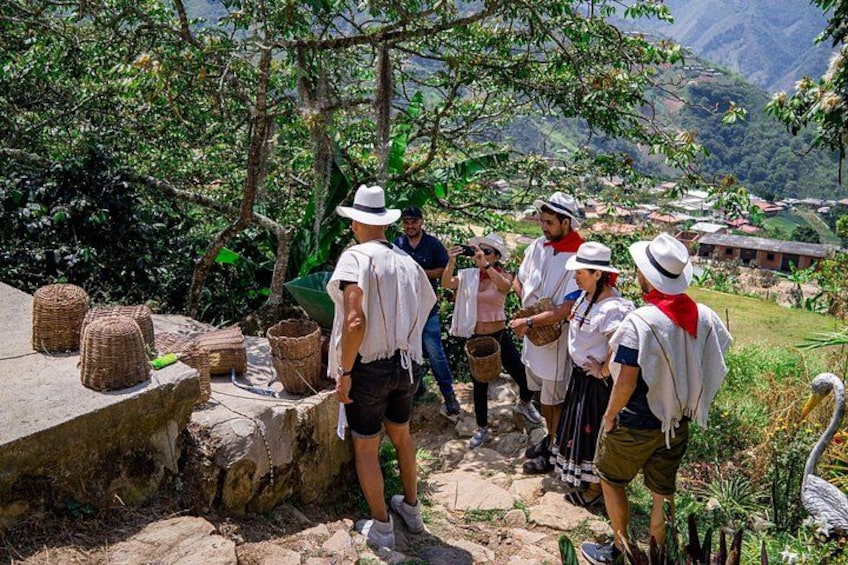 A group of people in traditional attire standing on a stone path surrounded by greenery and mountains in the background. 4
