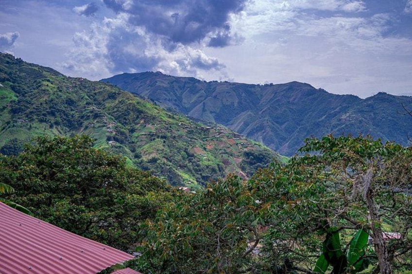 A mountainous landscape with dense greenery and a red-roofed building in the foreground. 2